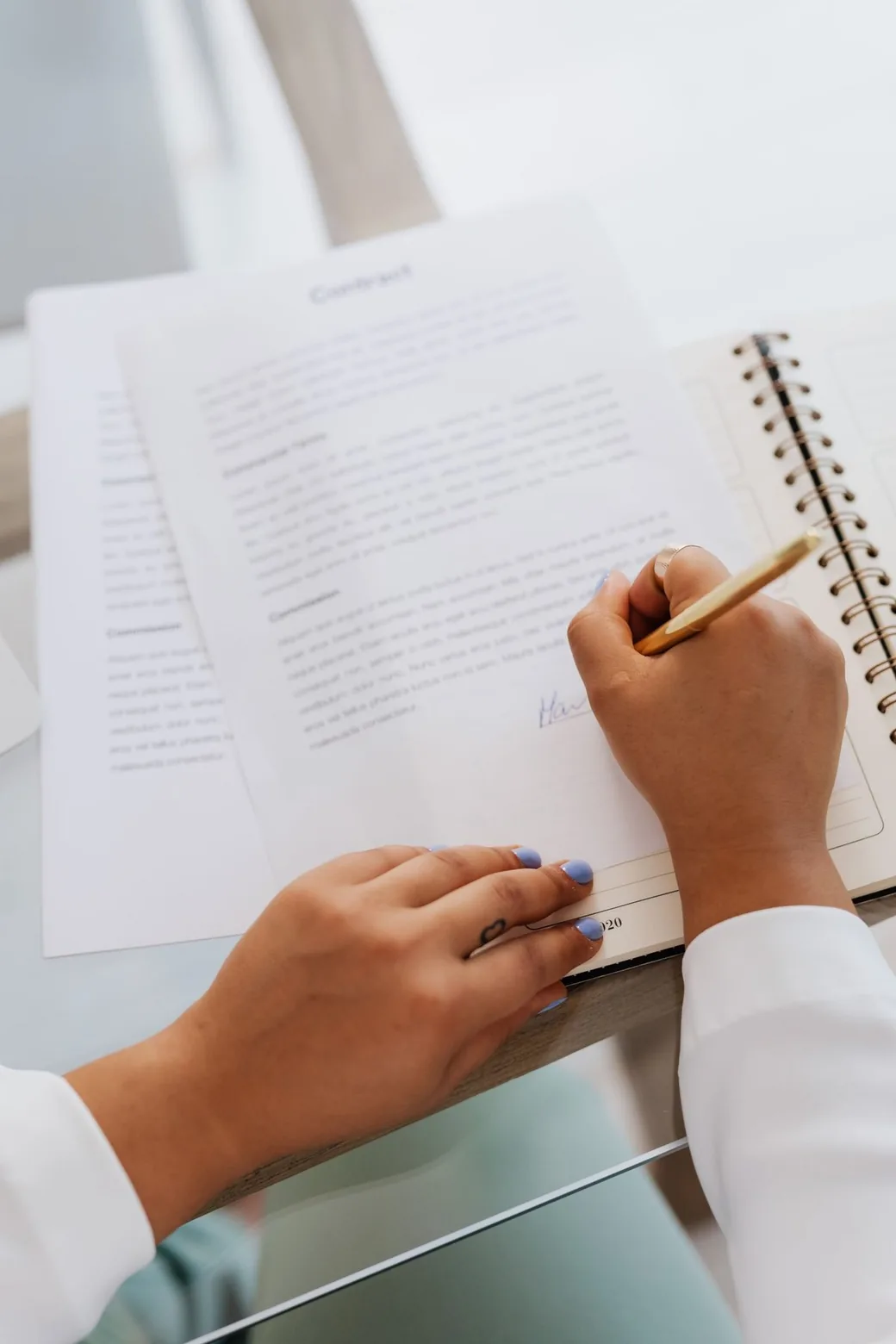 Main tenant un stylo doré en train de signer un contrat de pension posé sur une table, illustrant les mentions obligatoires à vérifier avant de s'engager