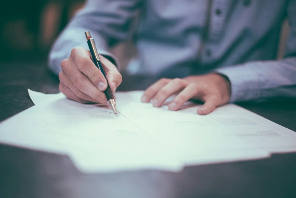 Une personne signant un document administratif, illustration des formalités de création d'entreprise