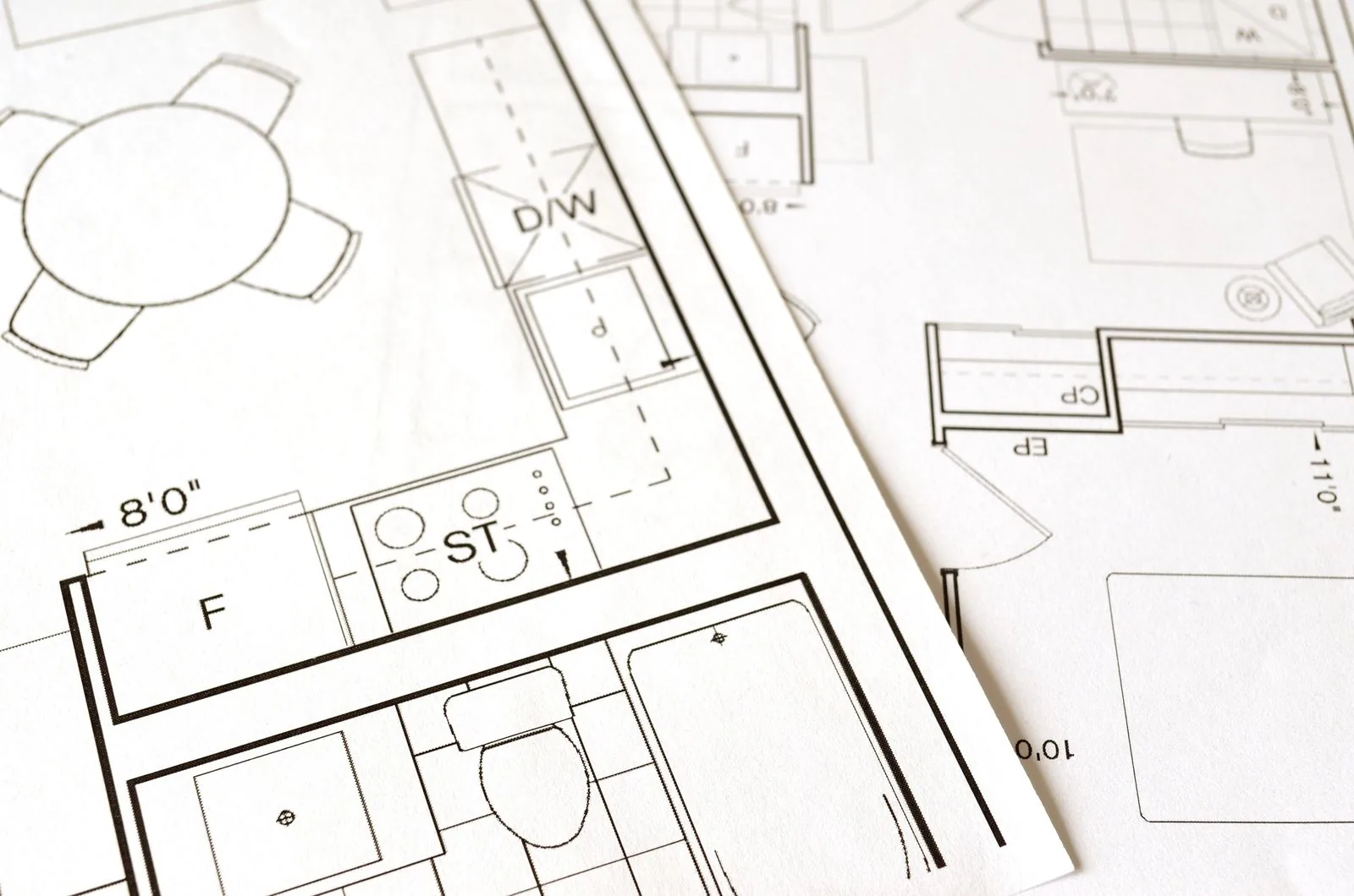 Plan d'aménagement d'une maison posé sur une table, évoquant les documents d'urbanisme et le permis à préparer avant de construire